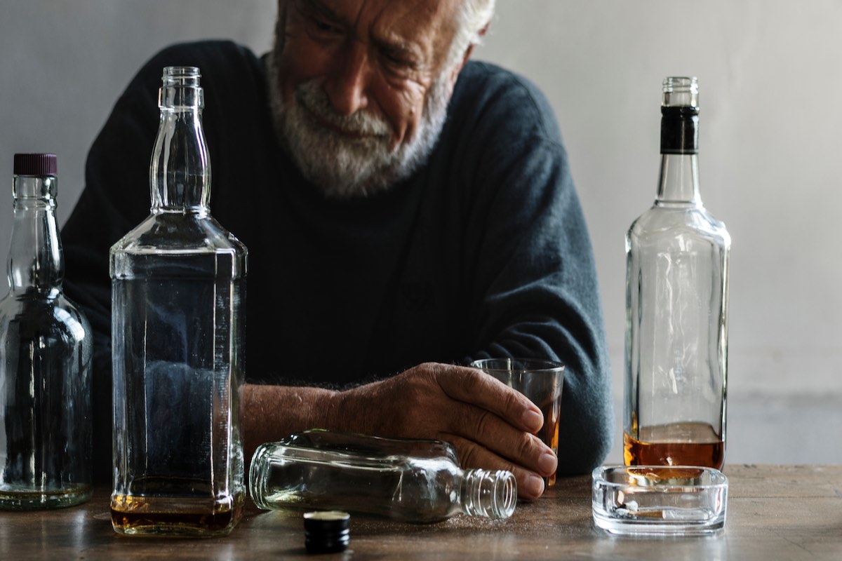 Elderly man crying while drinking alcohol