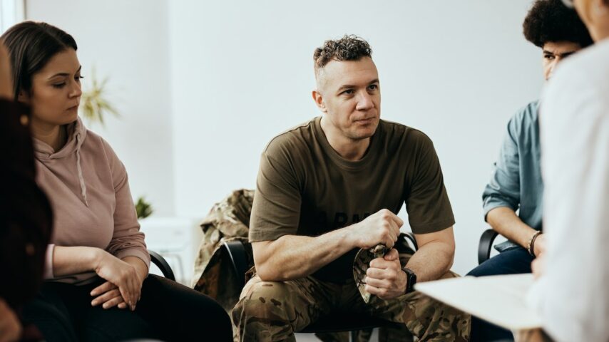Military officer listens to therapist during group therapy meeting at community center in California