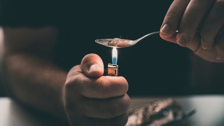 Addict at the table with a syringe heroin addiction