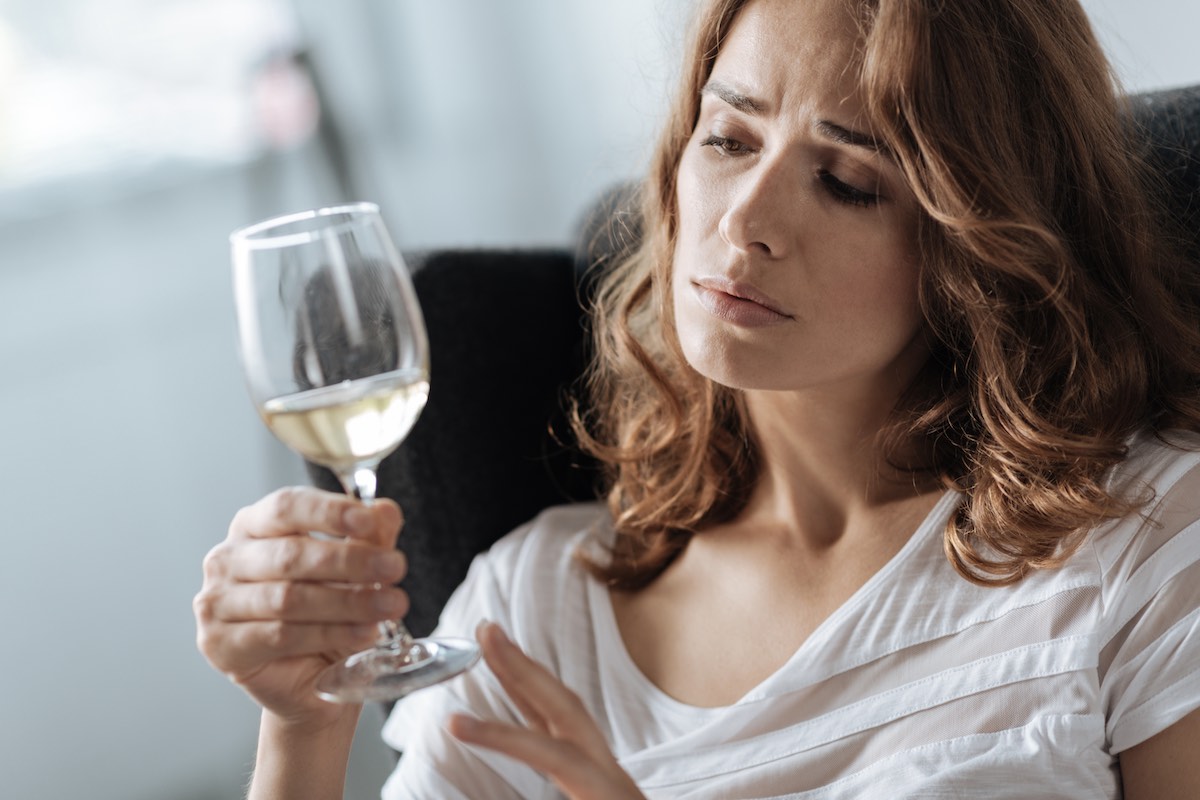 Unhappy beautiful woman staring at the glass of wine
