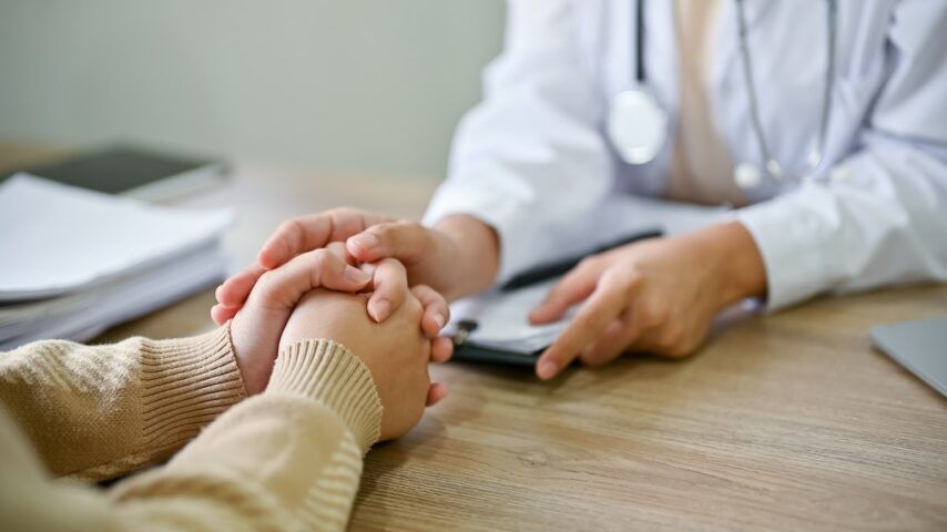 Close up view of doctor touching patient hand while explaining the AmeriHealth drug rehab insurance coverage