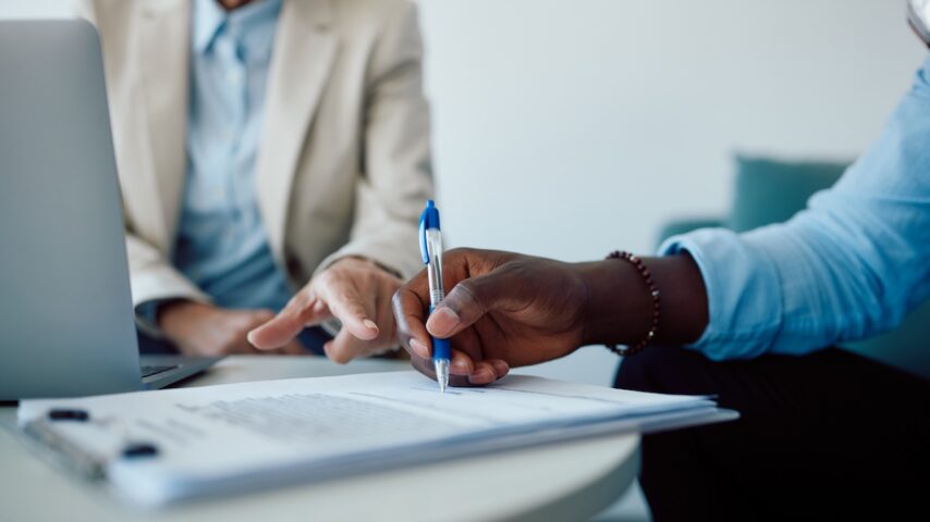 Close-up of black man signing contract with a Humana insurance agent