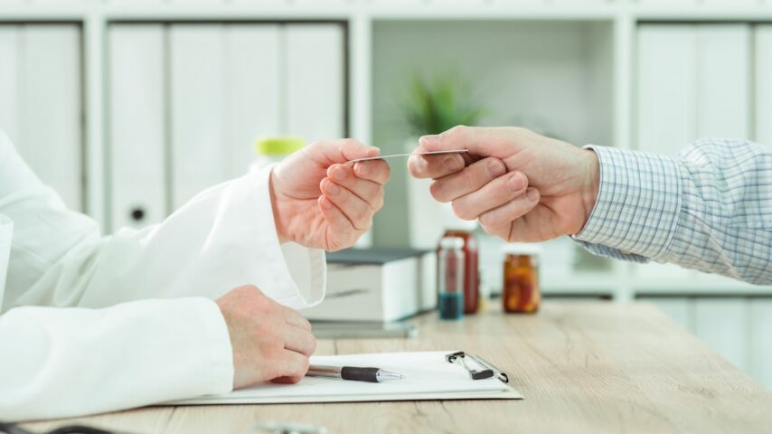 Doctor taking Centene insurance card from patient in office during scheduled checkup