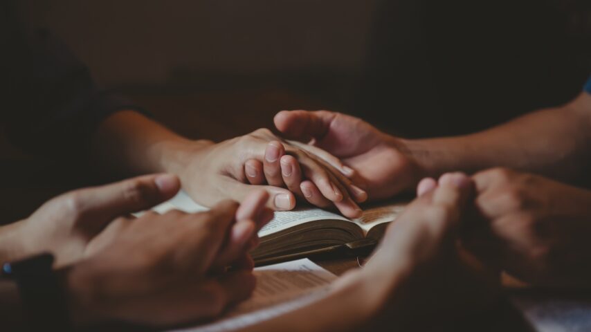 A group of people praying with the bible in a faith-based rehab center