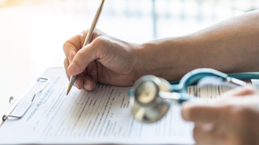 Medical doctor writing on patient personal health care record form for Harvard Pilgrim insurance rehab coverage