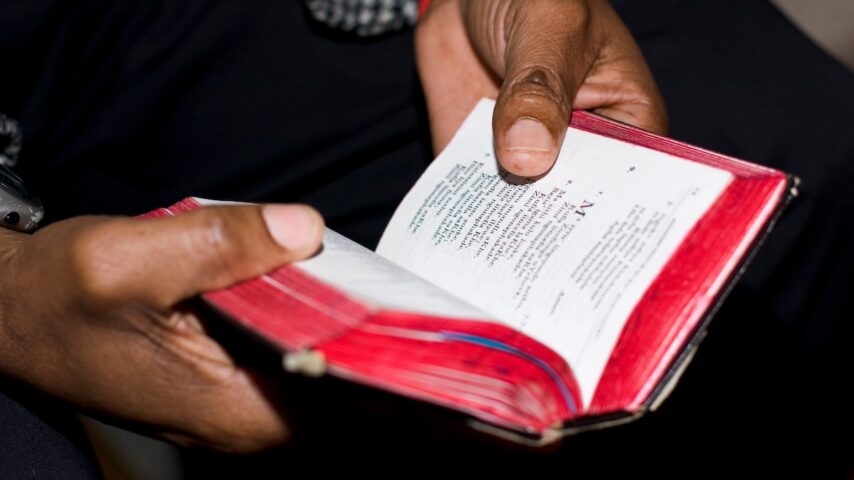 Two hands holding an old, well-used prayer book at a Methodist church service on Sunday