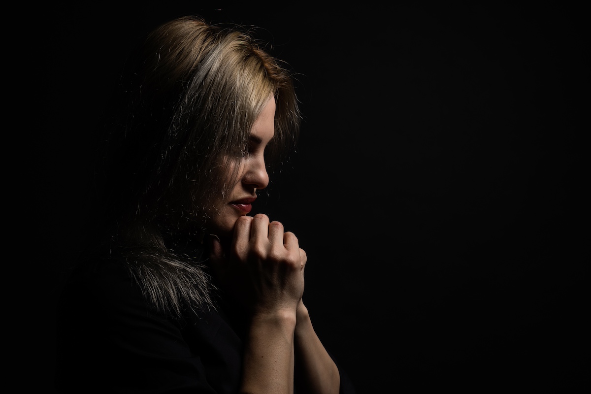 Pentecostal woman praying with hands together on black background